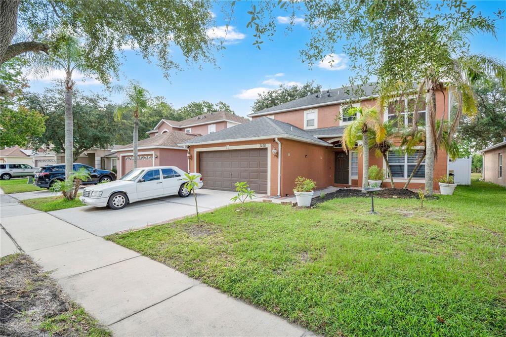 A two-story house with a brown garage, a white sedan, and palm trees in the yard — 3230 ERSKINE DRIVE, ORLANDO, FL