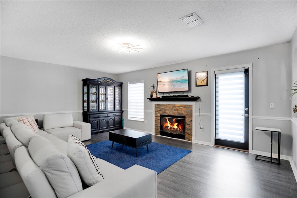 A living room features a stone fireplace, a white sectional sofa, and a blue rug — 3230 ERSKINE DRIVE, ORLANDO, FL