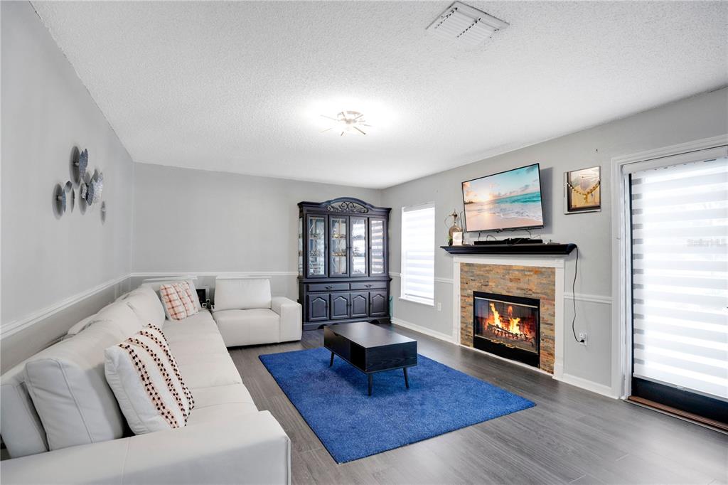 A living room features a white sofa, a blue rug, and a stone fireplace — 3230 ERSKINE DRIVE, ORLANDO, FL