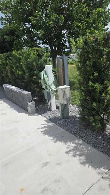 An outdoor utility area features electrical pedestals and a hose near a concrete driveway — 237 BAINBRIDGE DRIVE, NOKOMIS, FL