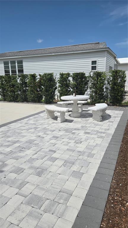 A stone patio features a round table and three curved benches beside a house — 237 BAINBRIDGE DRIVE, NOKOMIS, FL