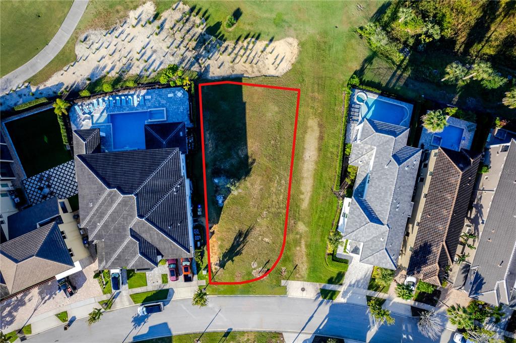 An aerial view shows a vacant residential lot situated between two large, multi-story houses — 1188 CASTLE PINES COURT, REUNION, FL