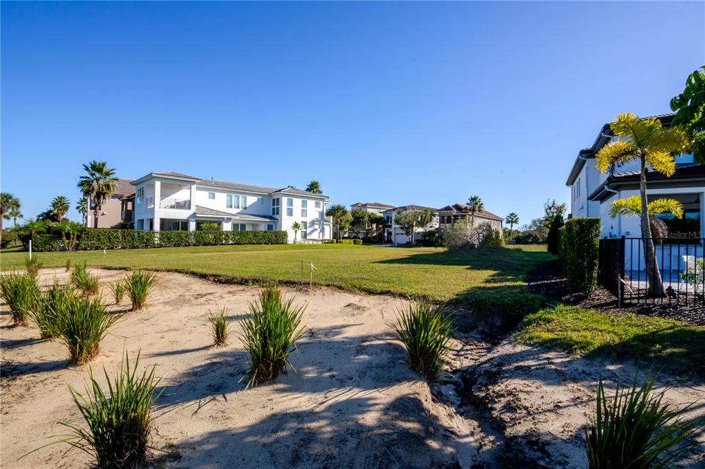 A white two-story house sits next to a large, grassy lot with palm trees — 1188 CASTLE PINES COURT, REUNION, FL