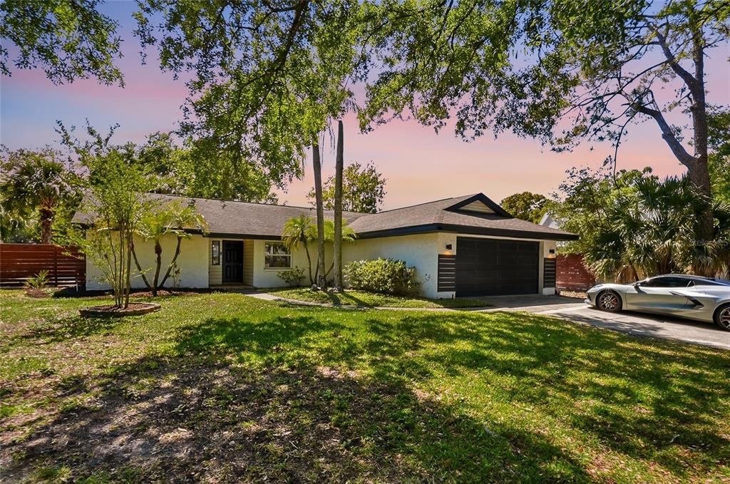 A single-story house with a white exterior, dark garage door, and a parked silver car — 4606 BUCKEYE ROAD, TAMPA, FL