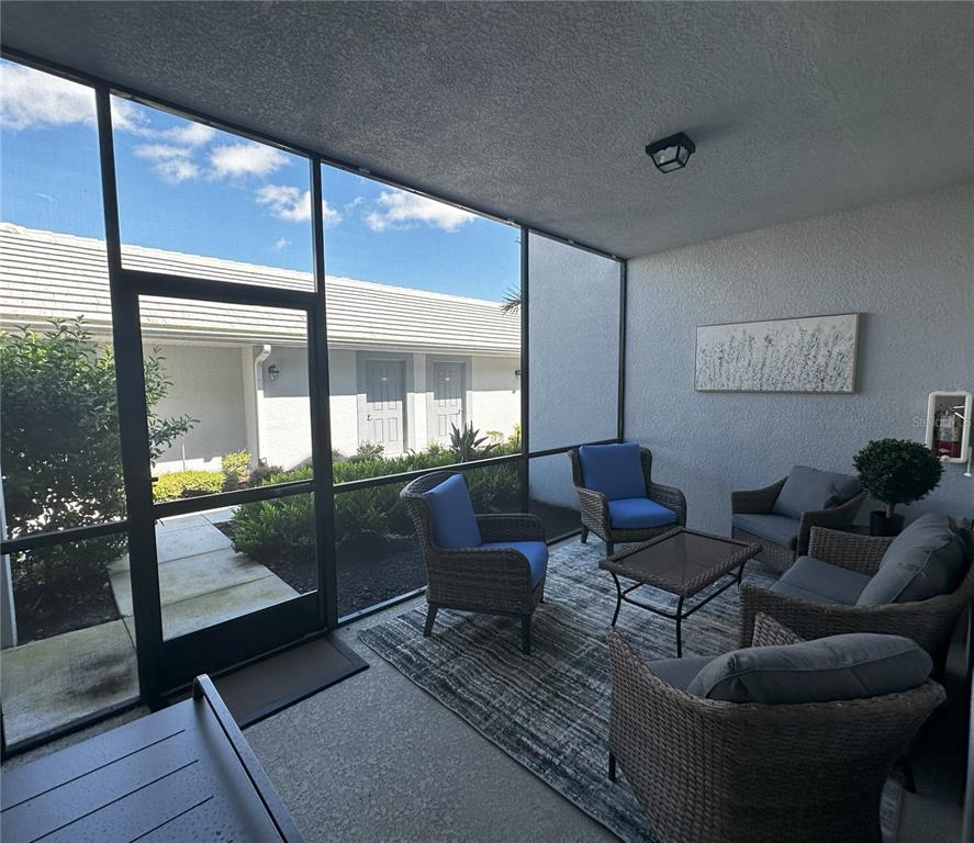 A screened-in patio features wicker furniture, a patterned rug, and views of a neighboring building — 14040 HERITAGE LANDING BOULEVARD UNIT 116, PUNTA GORDA, FL