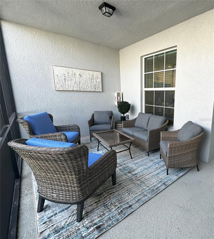 A screened-in patio features wicker furniture with blue and gray cushions on a patterned rug — 14040 HERITAGE LANDING BOULEVARD UNIT 116, PUNTA GORDA, FL