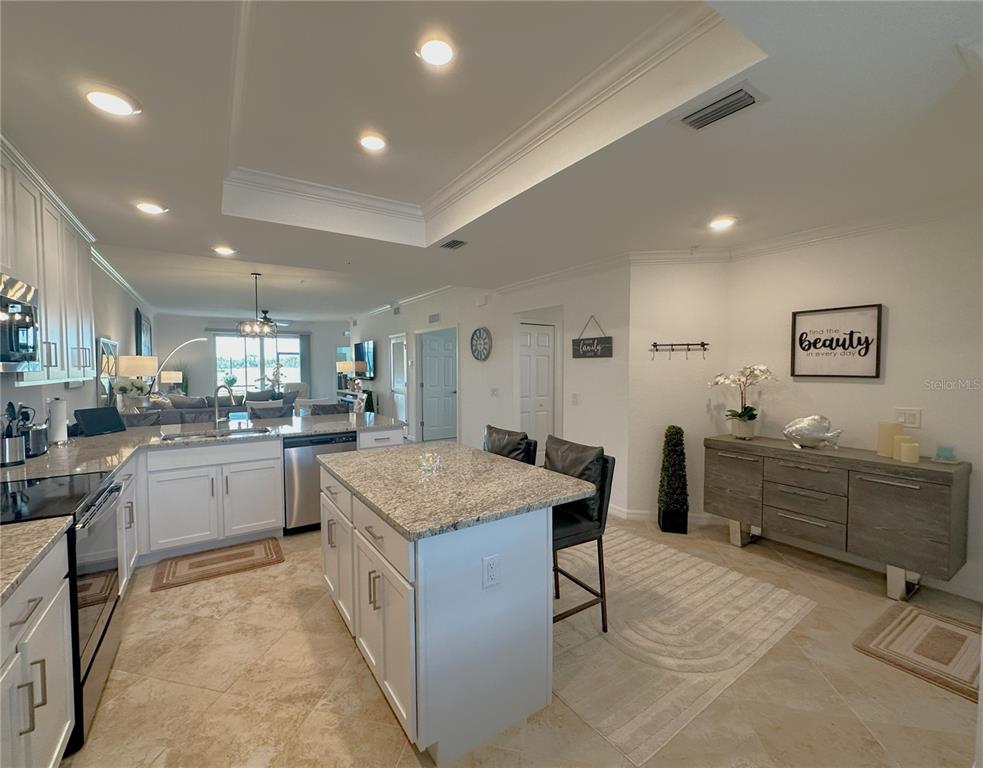 A kitchen with white cabinets, granite countertops, a center island, and an adjacent dining area — 14040 HERITAGE LANDING BOULEVARD UNIT 116, PUNTA GORDA, FL