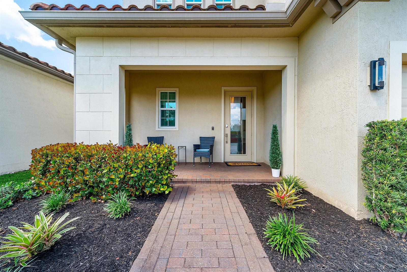 A brick walkway leads to a covered front porch with two chairs and a door — 4767 Marston Lane, Lake Worth FL 33467, LAKE WORTH, FL