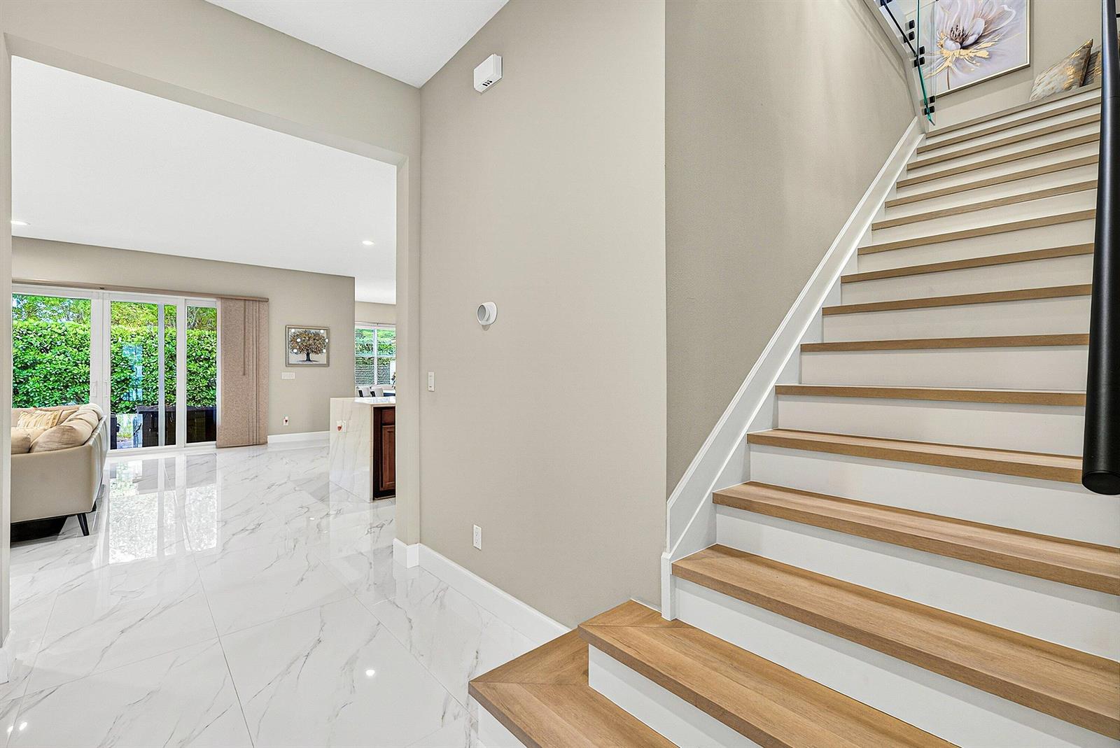 A staircase with wood treads and white risers leads up beside a tiled living area — 4767 Marston Lane, Lake Worth FL 33467, LAKE WORTH, FL