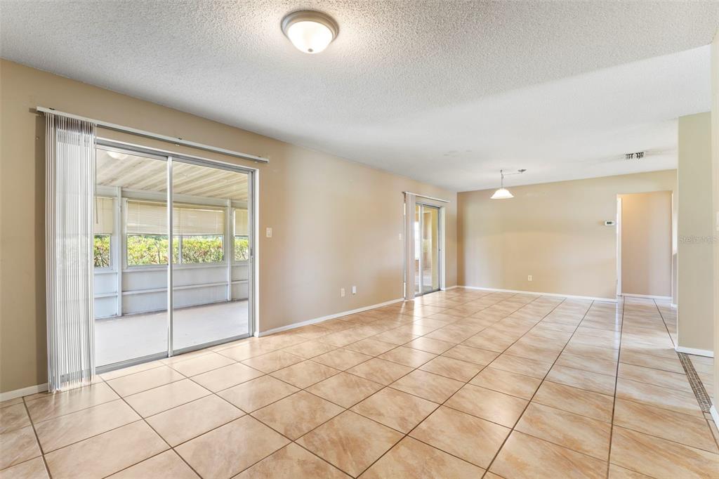 An open-concept living area features beige tile flooring, light-colored walls, and sliding glass doors — 10312 LAZY LAKE DRIVE, ORLANDO, FL