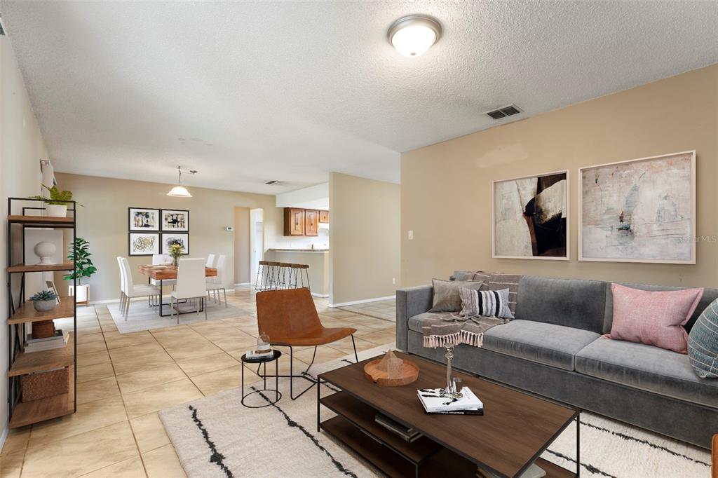 A living room with tile floors, a grey sofa, and an adjacent dining area — 10312 LAZY LAKE DRIVE, ORLANDO, FL