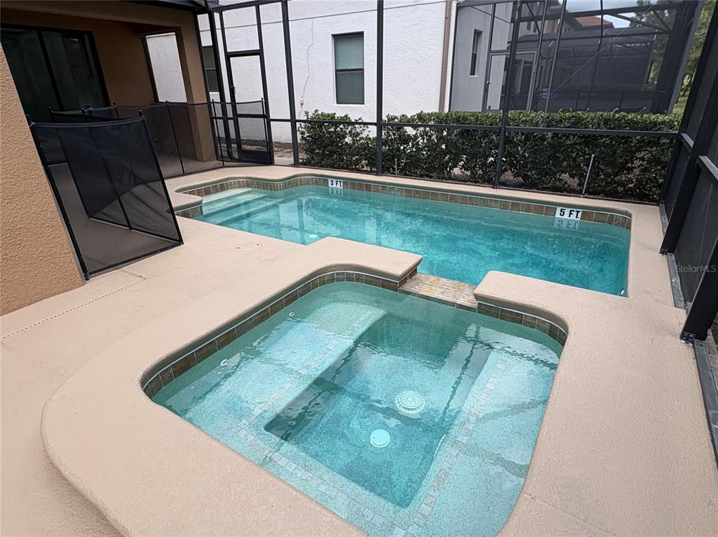 A screened-in patio features a rectangular swimming pool and an attached square hot tub — 5408 SOLTERRA CIRCLE, DAVENPORT, FL
