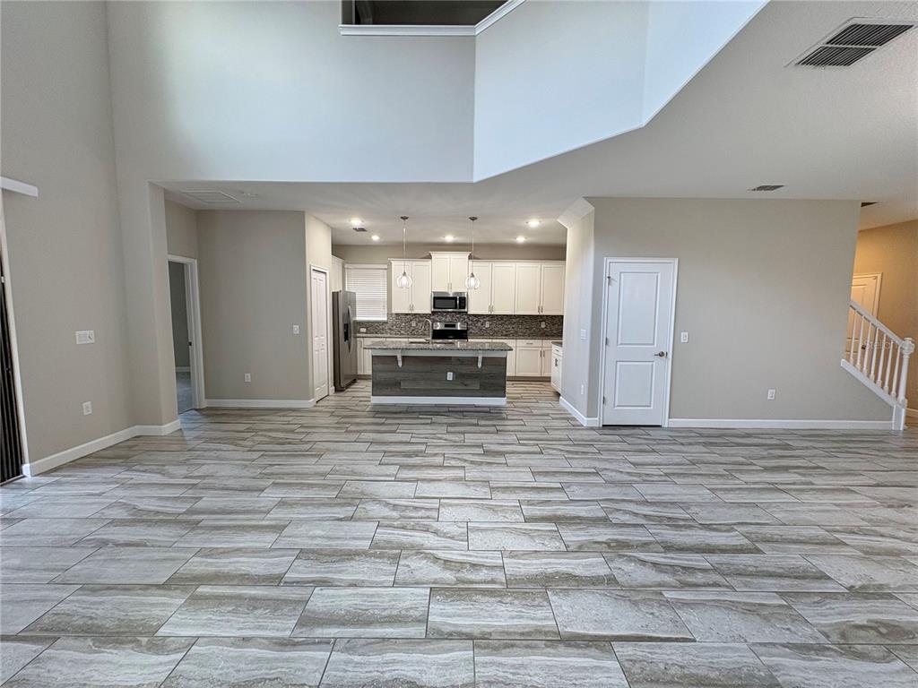 A spacious open-concept kitchen features white cabinetry, a center island, and light-toned tile flooring — 5408 SOLTERRA CIRCLE, DAVENPORT, FL