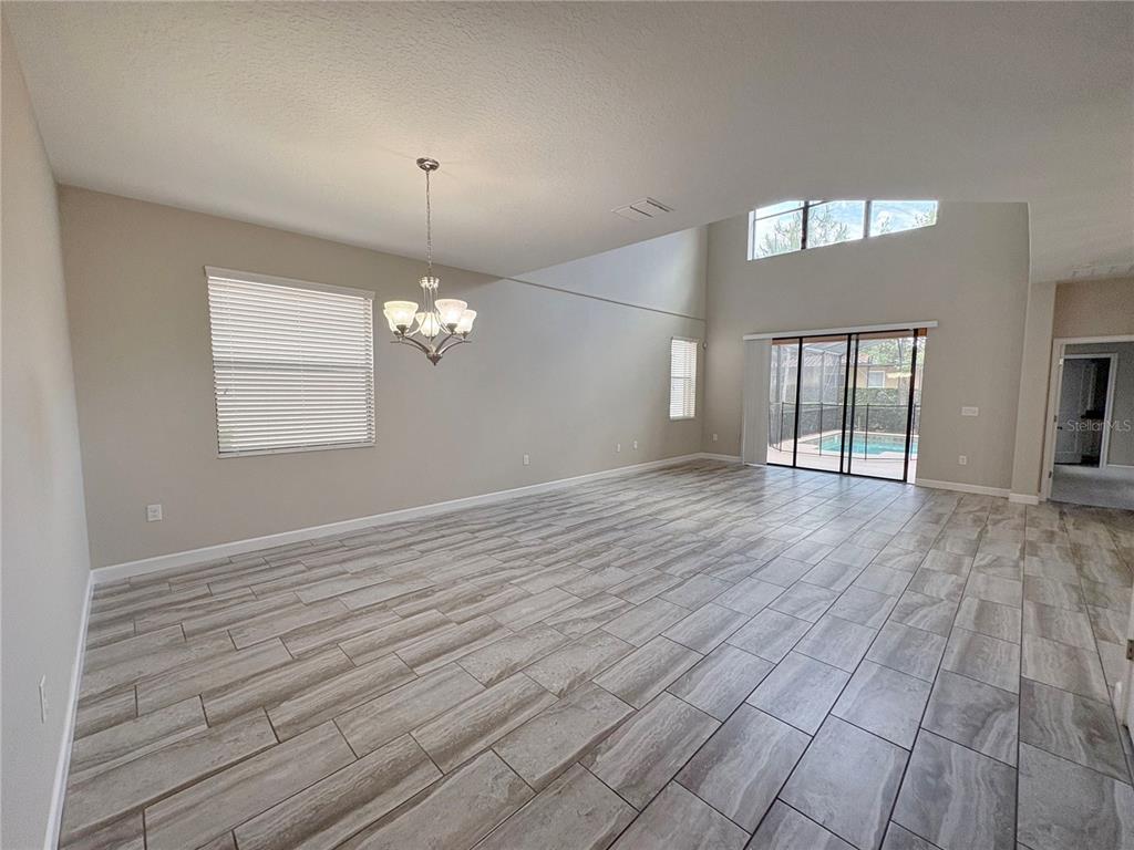 A spacious living area features light-colored tile flooring, a vaulted ceiling, and sliding glass doors — 5408 SOLTERRA CIRCLE, DAVENPORT, FL