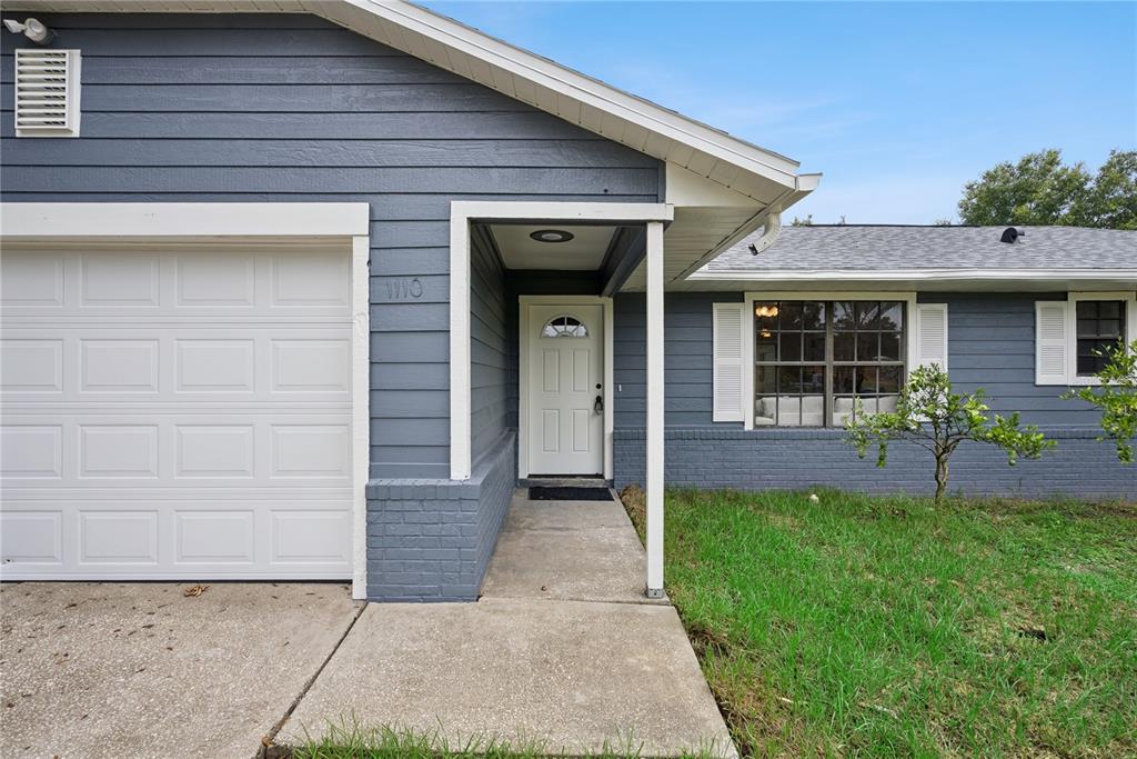 The exterior of a blue house features a white garage door and a front entrance — 1110 CATHERINE STREET, ORANGE CITY, FL