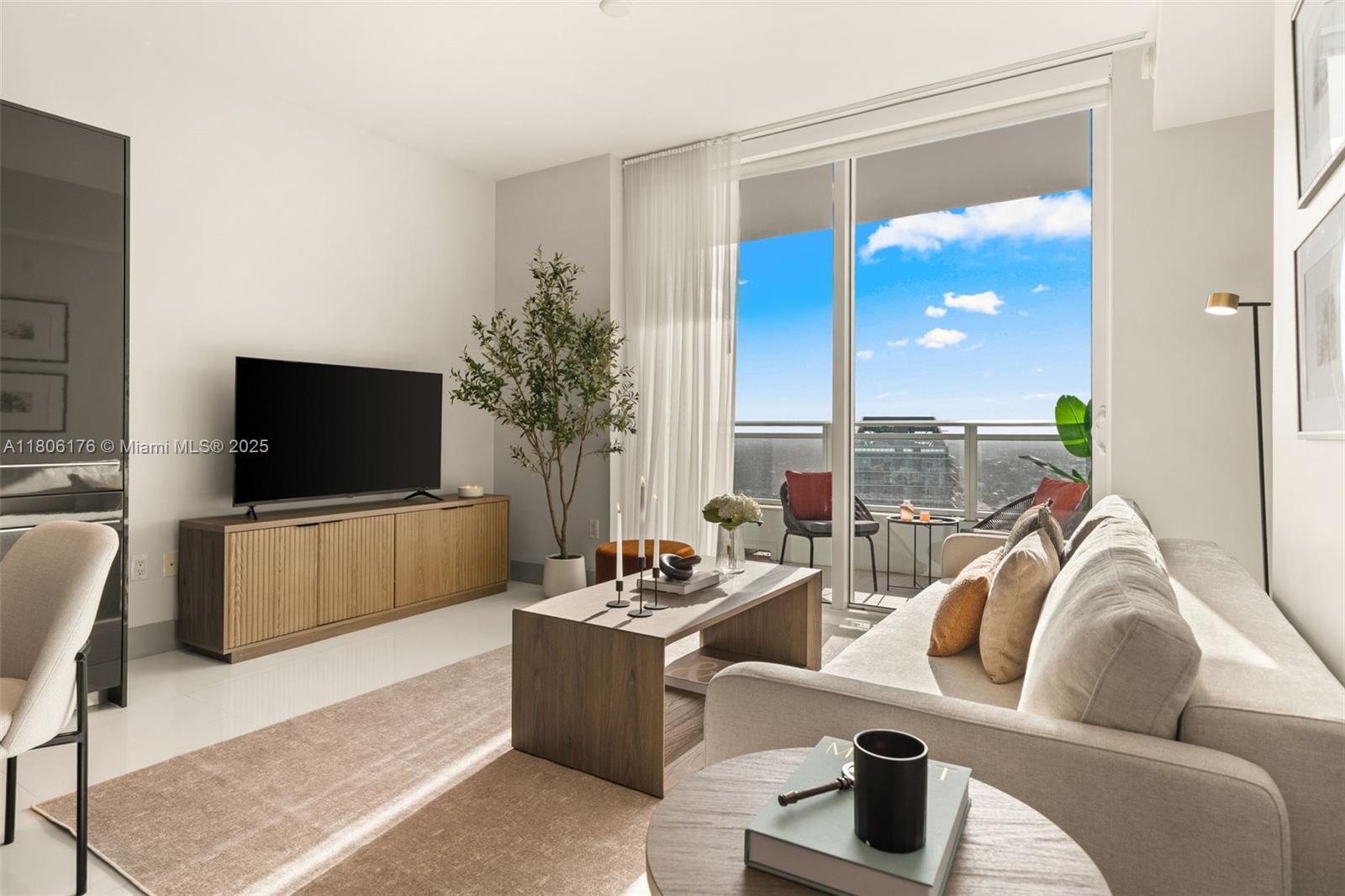 A modern living room features a sofa, television, coffee table, and a balcony with city views — 1080 Brickell Ave # 3905, Miami FL 33131, MIAMI, FL