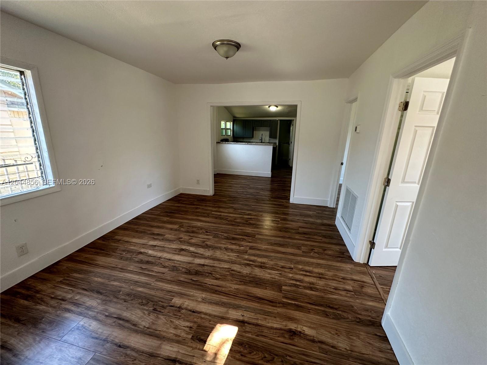 A living room with wood-look flooring leads into a kitchen through a wide doorway — 5646 NW 3rd Ave # 1, Miami FL 33127, MIAMI, FL