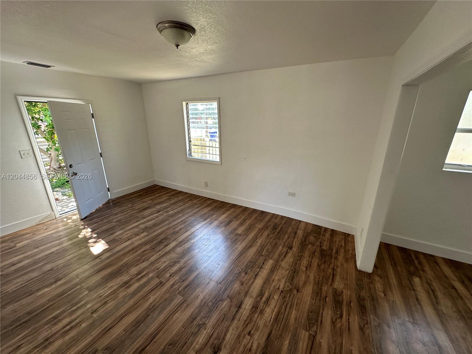 An empty room features white walls, wood-look flooring, a ceiling light, and an open door — 5646 NW 3rd Ave # 1, Miami FL 33127, MIAMI, FL