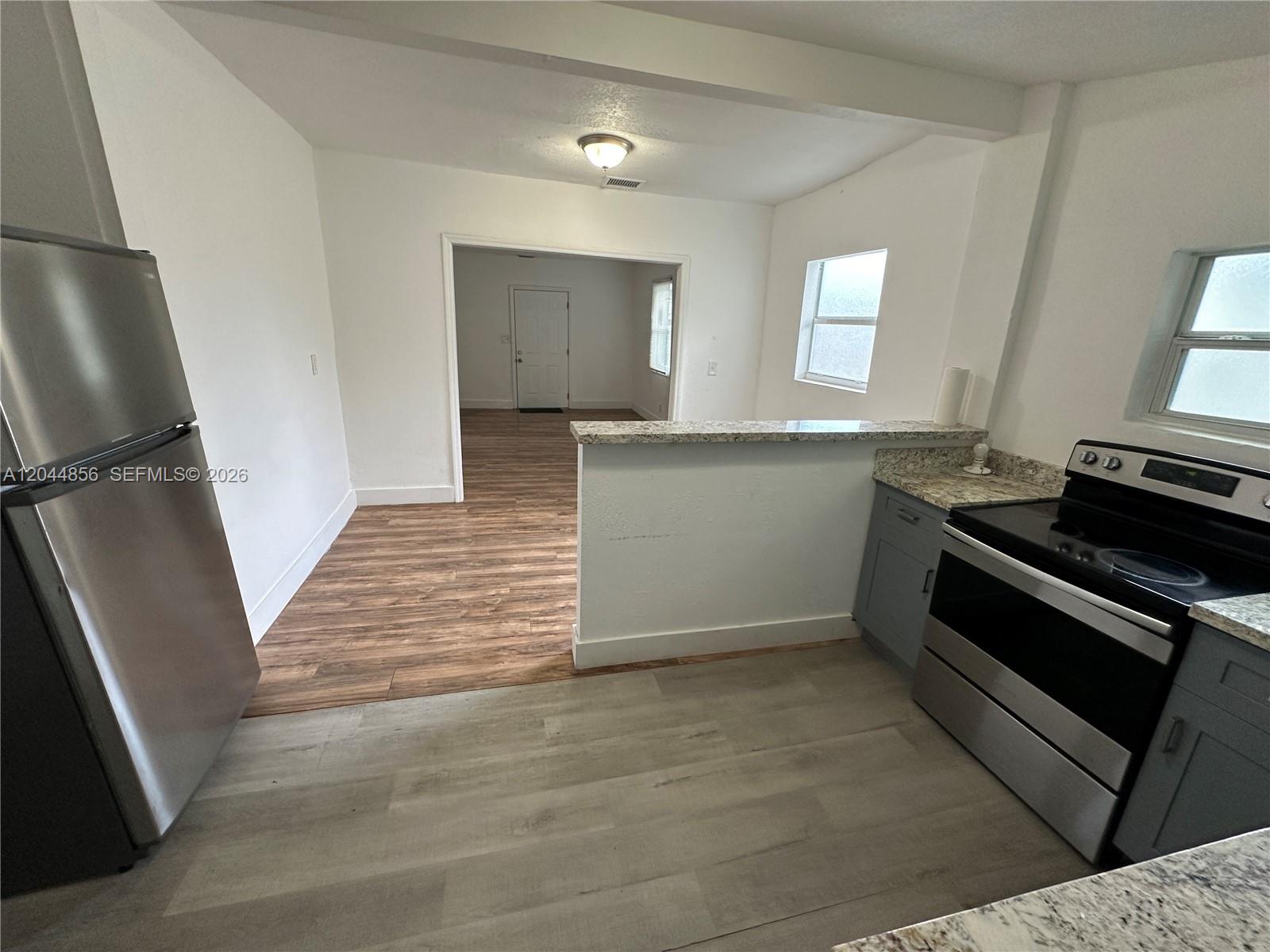 A kitchen with stainless steel appliances and gray cabinets opens to a living area — 5646 NW 3rd Ave # 1, Miami FL 33127, MIAMI, FL