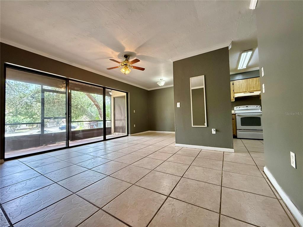 A living room with tile flooring, a ceiling fan, and a view of a patio — 2735 SW 35TH PLACE UNIT 601, GAINESVILLE, FL
