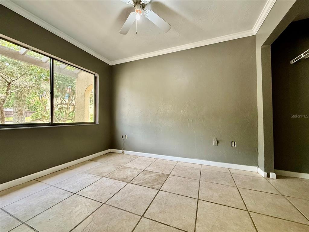 A room with beige tile flooring, olive-colored walls, a ceiling fan, and a large window — 2735 SW 35TH PLACE UNIT 601, GAINESVILLE, FL