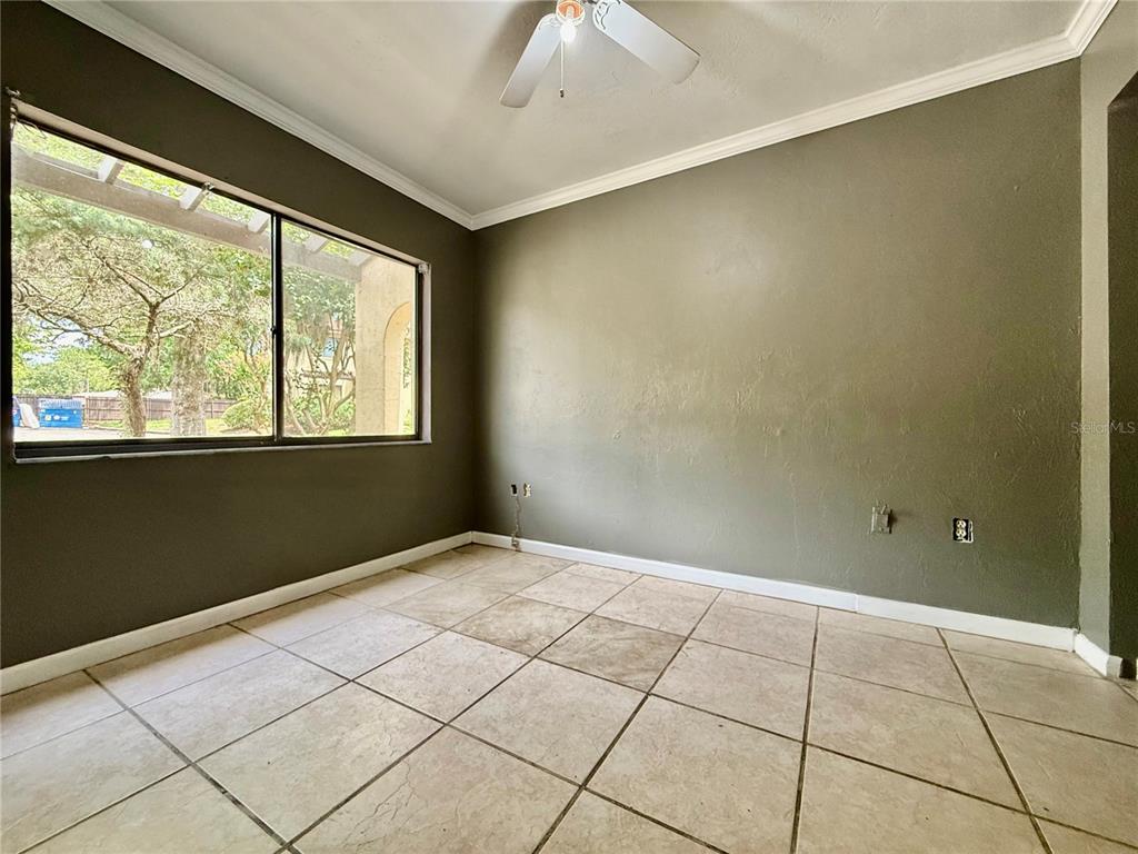 An empty room with olive green walls, tile flooring, a ceiling fan, and large windows — 2735 SW 35TH PLACE UNIT 601, GAINESVILLE, FL