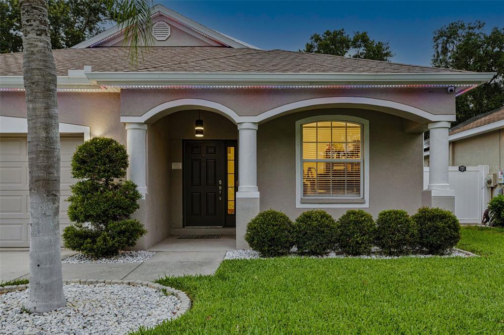 The exterior of a single-story house features a covered entryway with columns and landscaping — 12816 CATTAIL SHORE LANE, RIVERVIEW, FL
