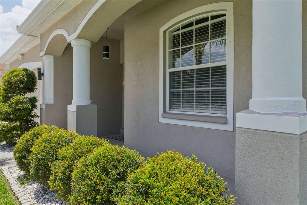 A beige house exterior features a covered entryway with white columns and a front window — 12816 CATTAIL SHORE LANE, RIVERVIEW, FL