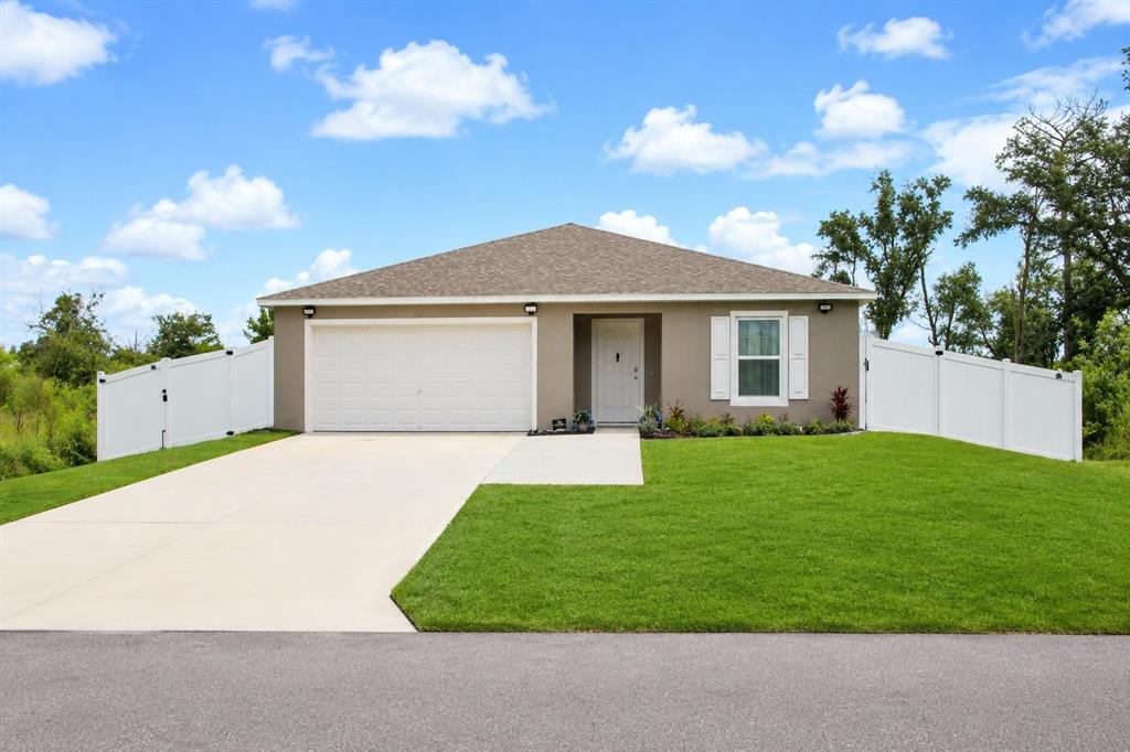 A single-story house with a white garage door, tan exterior, and white vinyl privacy fencing — 120 SPARROW COURT, POINCIANA, FL