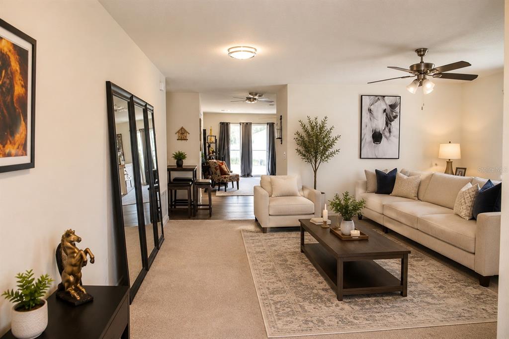A living room features a beige sofa, a coffee table, and a large floor mirror — 120 SPARROW COURT, POINCIANA, FL