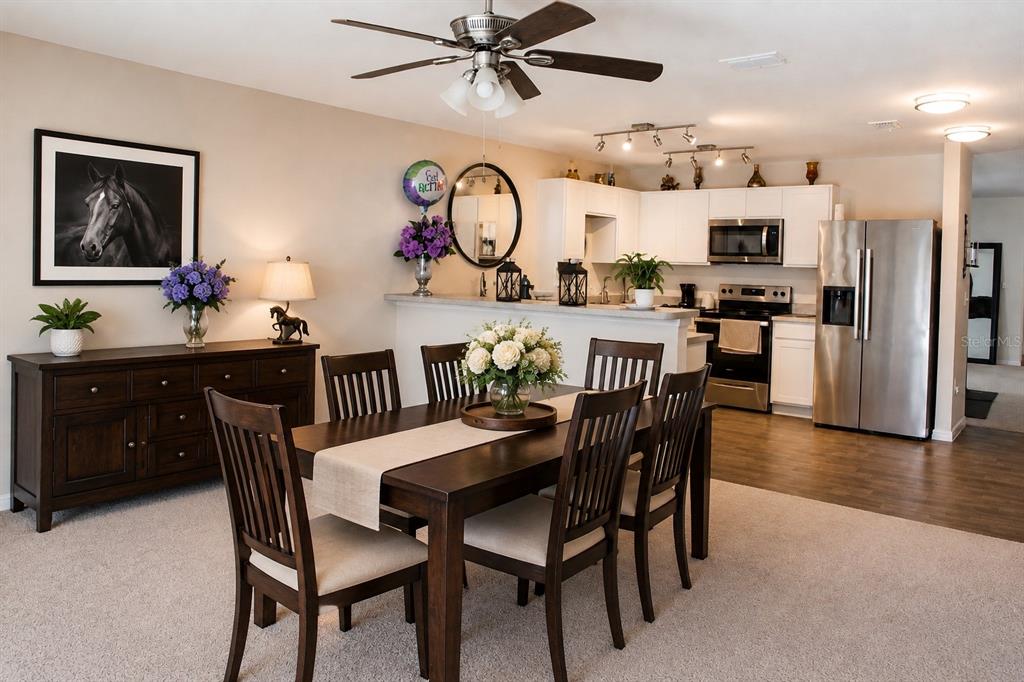 A dining area with a dark wood table and chairs sits before an open kitchen — 120 SPARROW COURT, POINCIANA, FL
