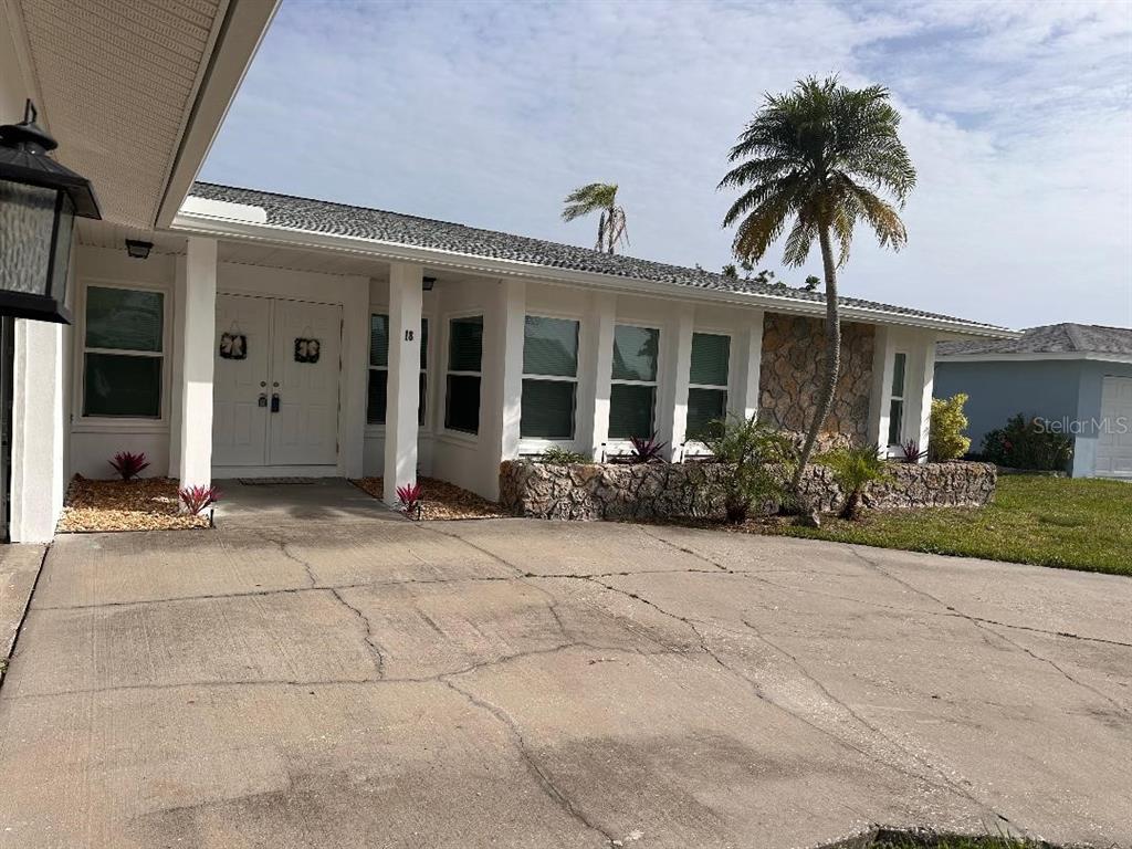 A white house with a stone facade, a palm tree, and a cracked concrete driveway — 18 GOLFVIEW COURT, ROTONDA WEST, FL