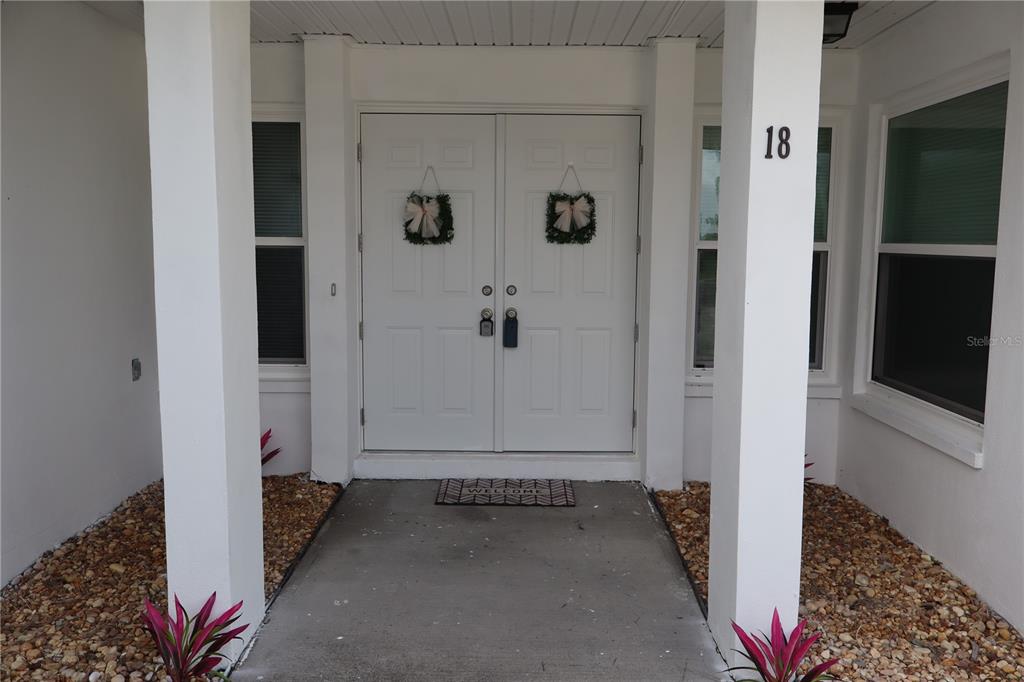 A white double front door with two wreaths is framed by two white columns — 18 GOLFVIEW COURT, ROTONDA WEST, FL