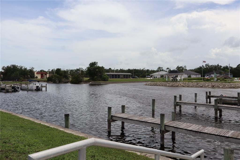 A view of a canal with wooden docks, boats, and houses in the background — 18 GOLFVIEW COURT, ROTONDA WEST, FL