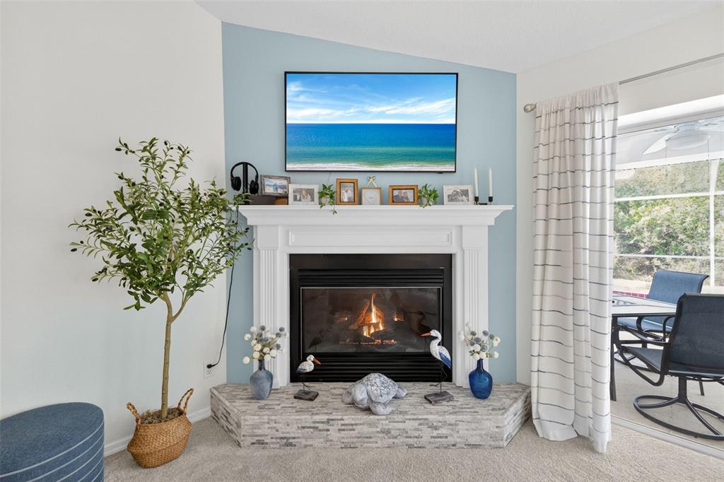 A living room features a corner fireplace with a stone hearth and a mounted television — 11905 LEON AVENUE, PORT CHARLOTTE, FL
