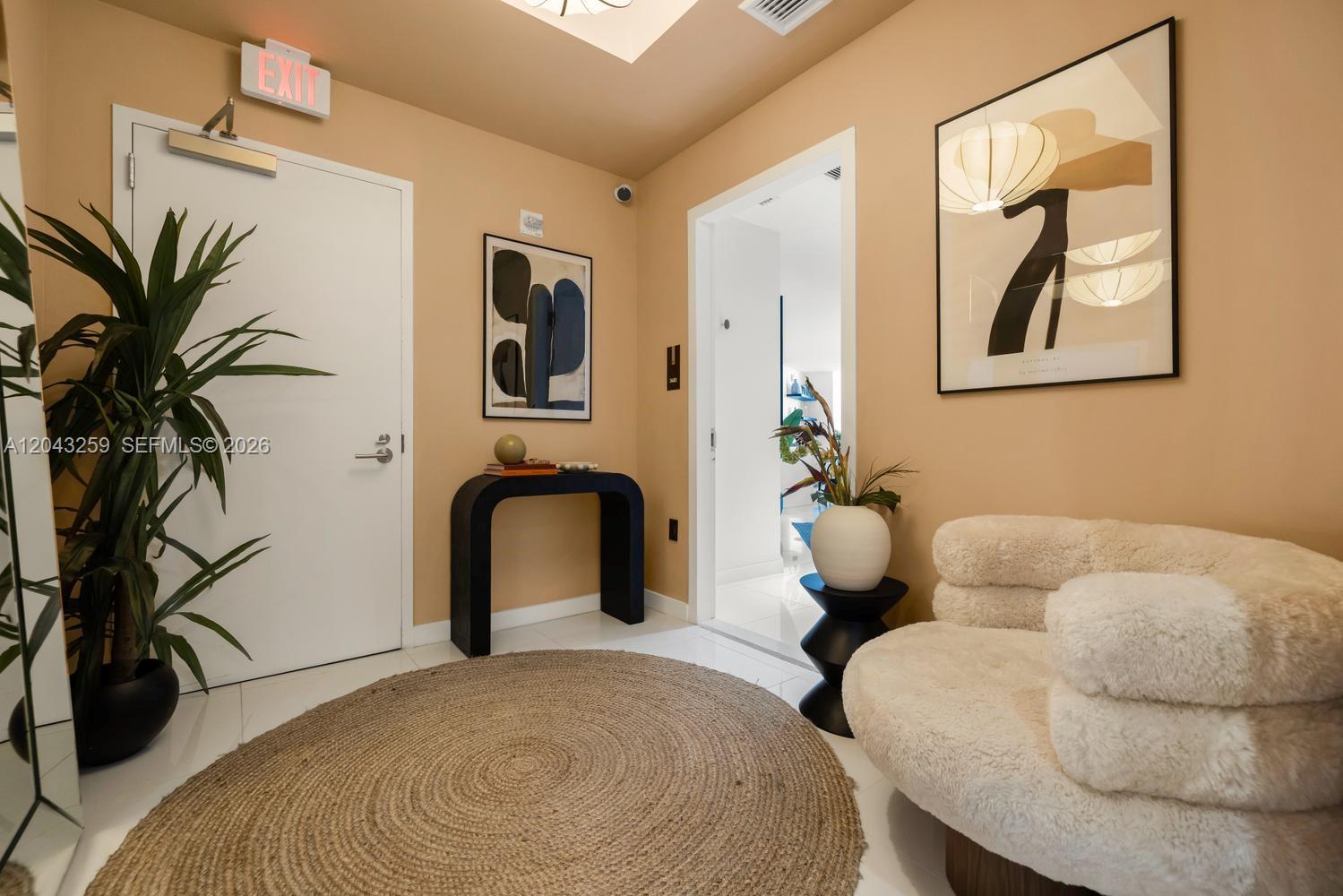 A modern entryway features a round jute rug, a fuzzy chair, and a black console table — 851 NE 1st Ave # 3403, Miami FL 33132, MIAMI, FL