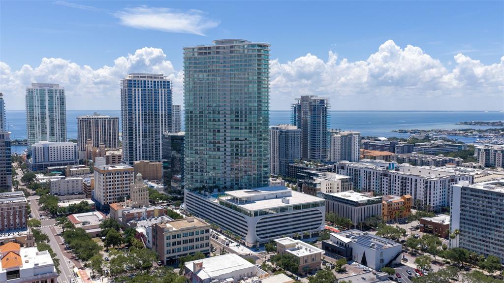 An aerial view shows a tall glass residential tower surrounded by other high-rise buildings — 400 CENTRAL AVENUE UNIT 3103, ST PETERSBURG, FL