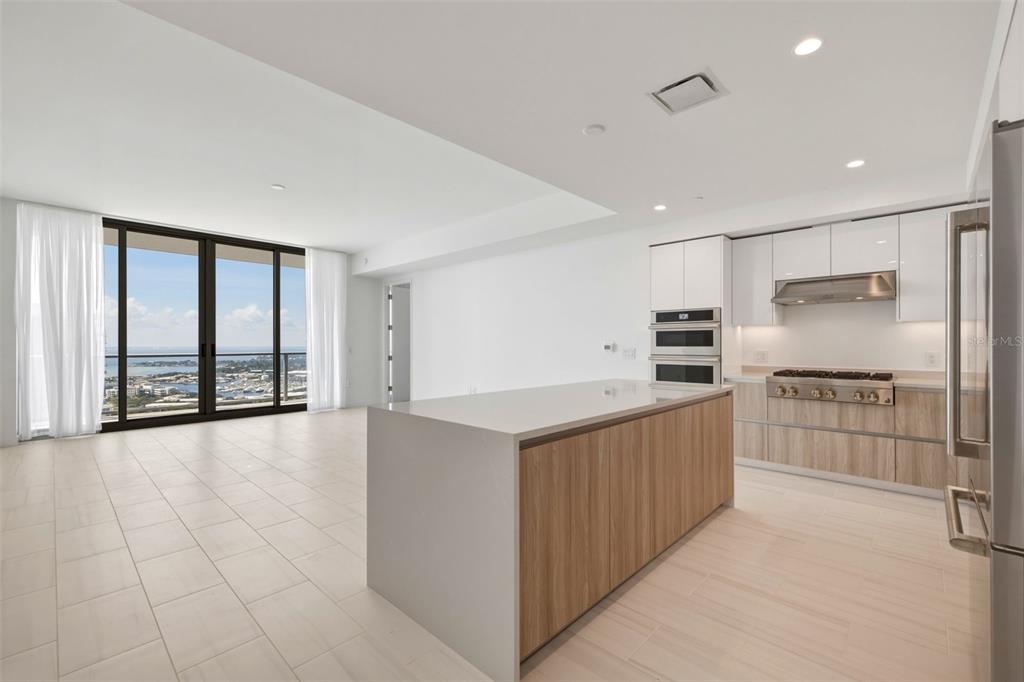 A modern kitchen with a central island, light wood cabinets, and floor-to-ceiling windows overlooking water — 400 CENTRAL AVENUE UNIT 3103, ST PETERSBURG, FL