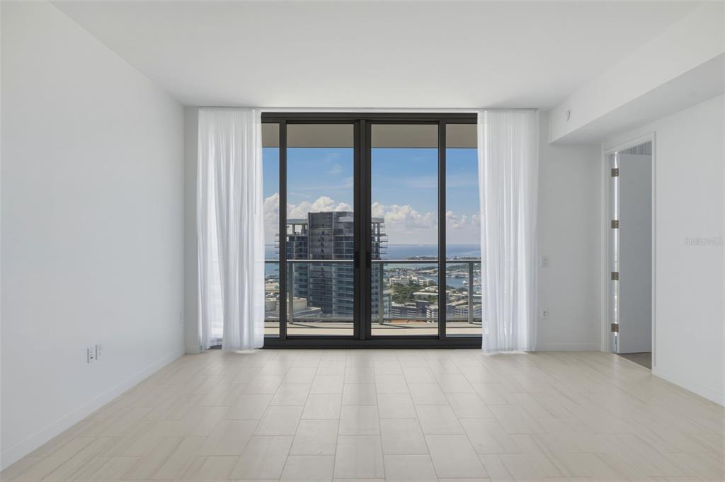 An empty room with light-colored tile flooring, white walls, and floor-to-ceiling windows overlooking a city — 400 CENTRAL AVENUE UNIT 3103, ST PETERSBURG, FL