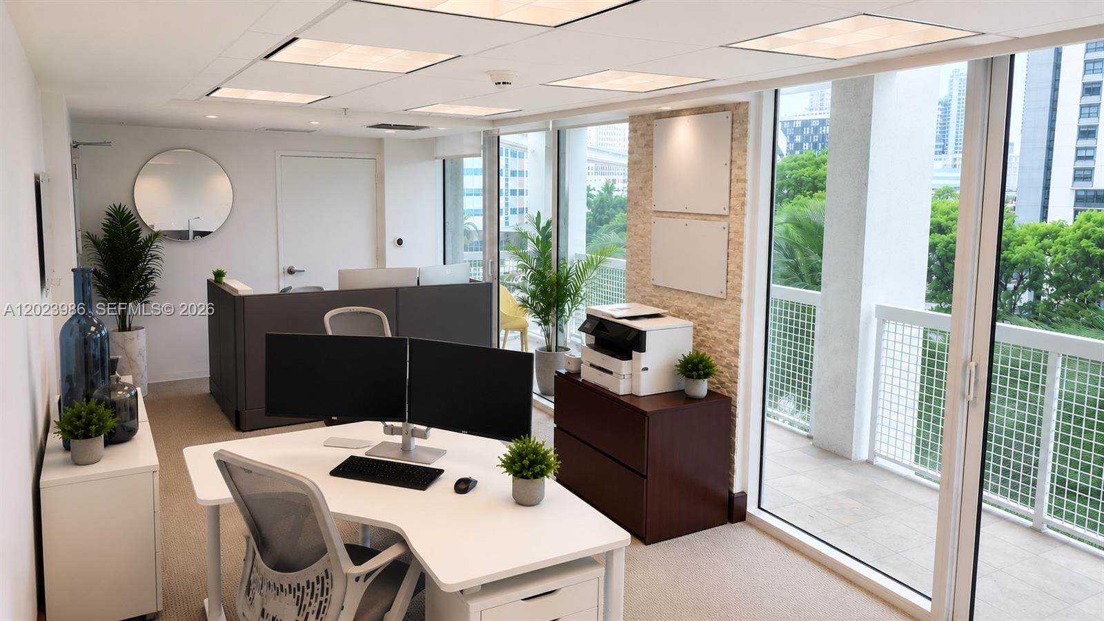 A modern office space features a white desk, dual monitors, and a balcony with city views — 31 SE 5th St # 502, Miami FL 33131, MIAMI, FL