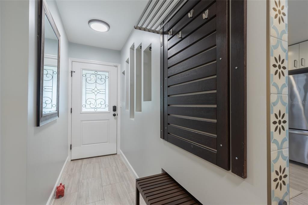 An entryway features a white door, a dark wood coat rack with a bench, and tile flooring — 2013 DOVER COURT, OLDSMAR, FL