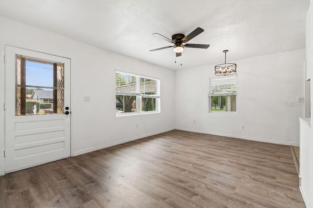 An empty room with white walls, wood-look flooring, a ceiling fan, and a light fixture — 203 PEVETTY DRIVE, PLANT CITY, FL