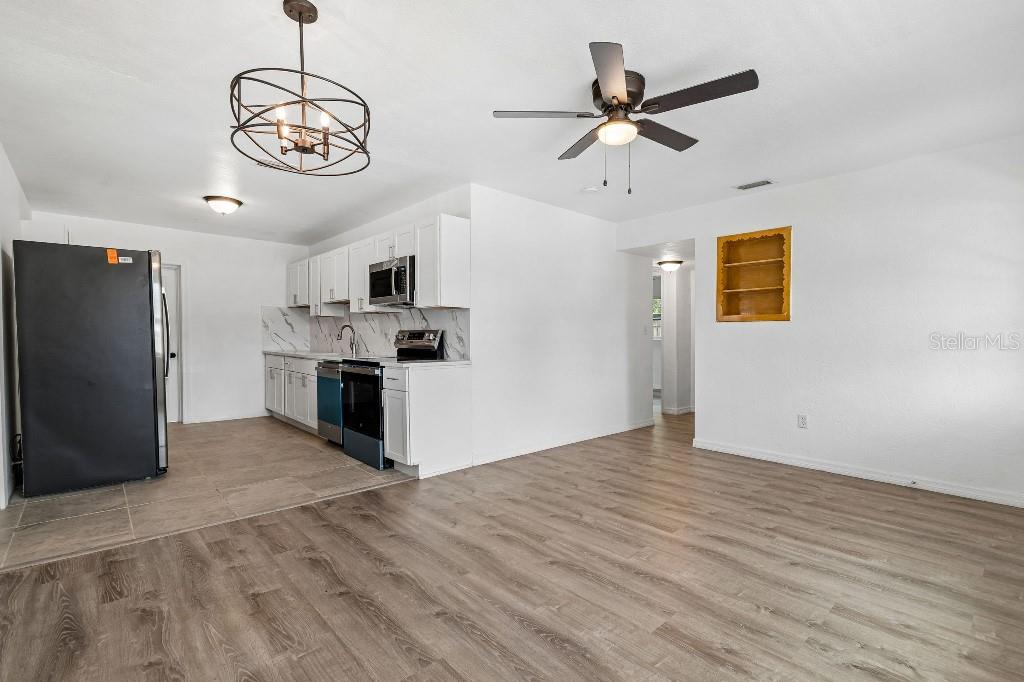 A kitchen with white cabinets, stainless steel appliances, and wood-look flooring in an open room — 203 PEVETTY DRIVE, PLANT CITY, FL
