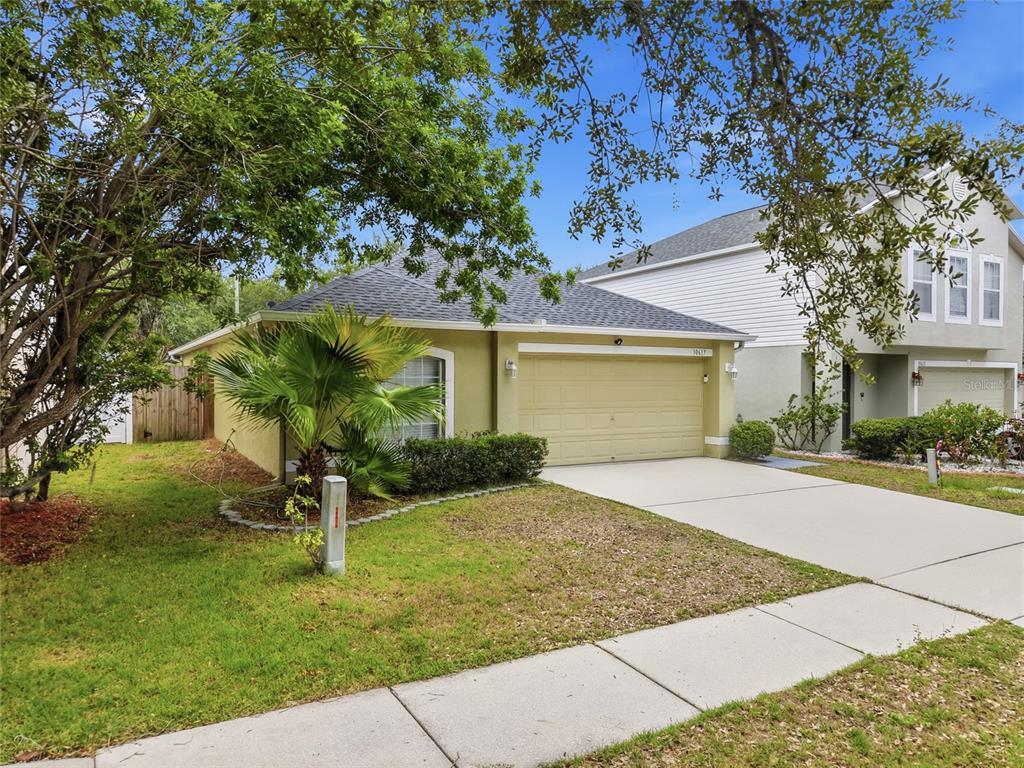 A one-story house with a tan exterior, a two-car garage, and a palm tree — 10617 OPUS DRIVE, RIVERVIEW, FL