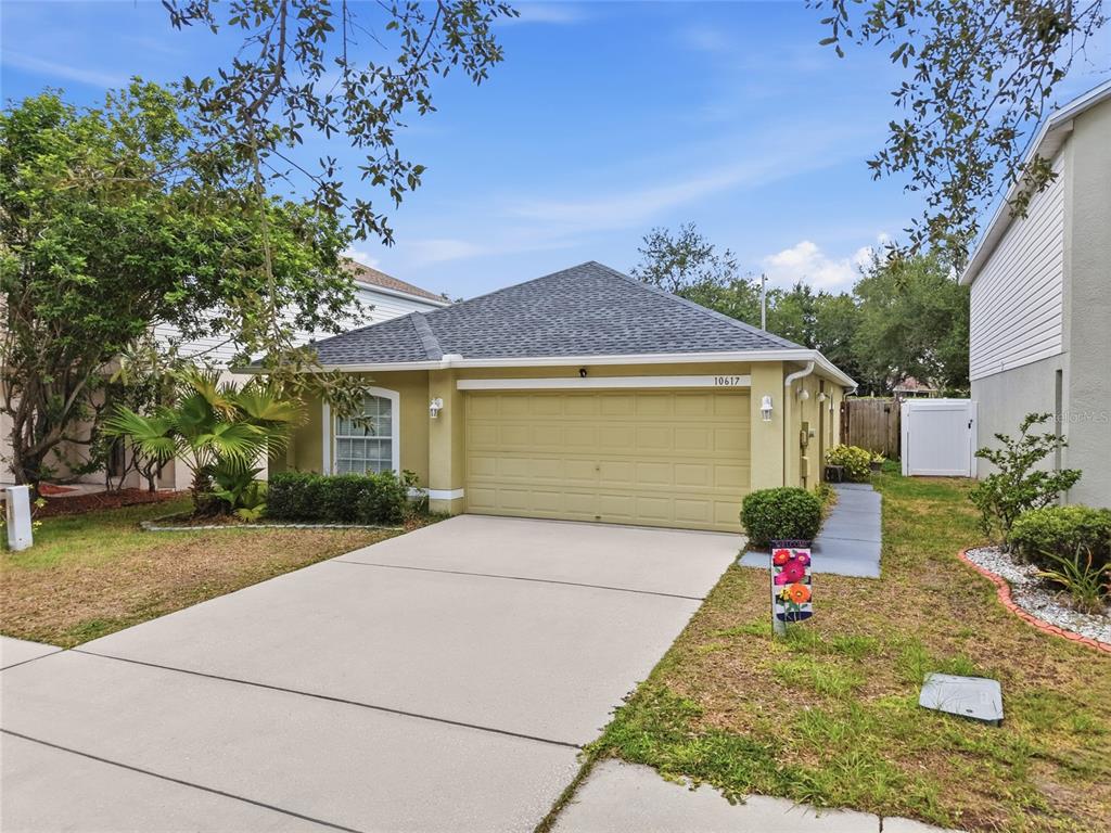 A single-story house with a tan exterior, a two-car garage, and a concrete driveway — 10617 OPUS DRIVE, RIVERVIEW, FL