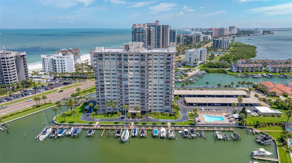 An aerial view of a tall waterfront condominium building with a marina and swimming pool — 1621 GULF BOULEVARD UNIT 501, CLEARWATER BEACH, FL