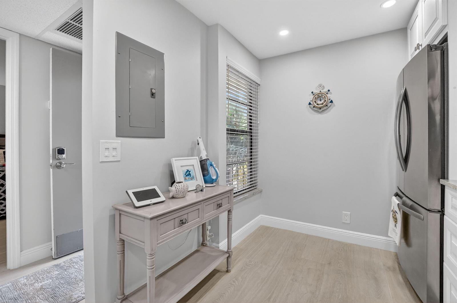 A light-colored kitchen area features a console table, a window with blinds, and a refrigerator — 6 Royal Palm Way # 409, Boca Raton FL 33432, BOCA RATON, FL