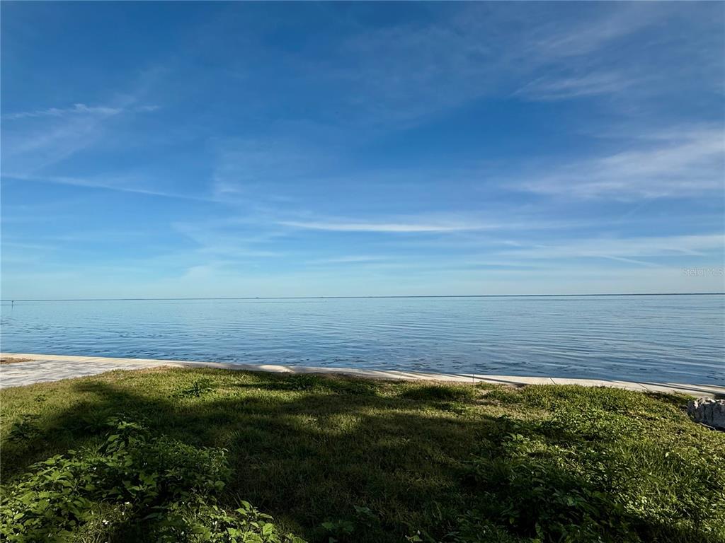 A grassy lawn overlooks a calm body of water under a blue sky — 5926 BAHAMA SHORES DRIVE S, ST PETERSBURG, FL