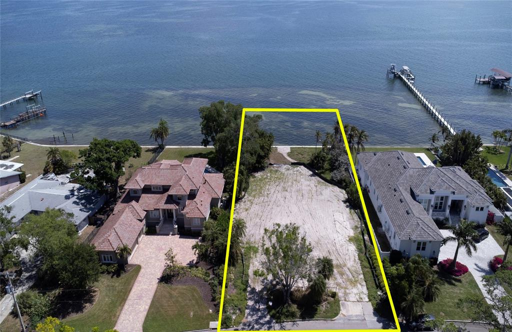 An aerial view shows a vacant waterfront lot situated between two large residential homes — 5926 BAHAMA SHORES DRIVE S, ST PETERSBURG, FL