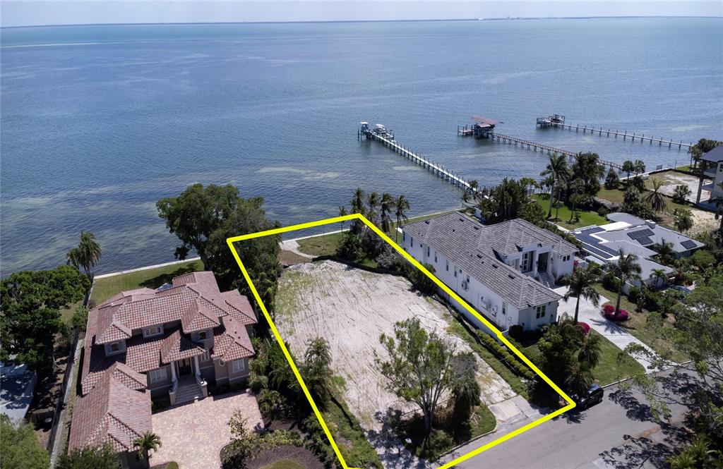 An aerial view shows a vacant waterfront lot outlined in yellow between two large houses — 5926 BAHAMA SHORES DRIVE S, ST PETERSBURG, FL